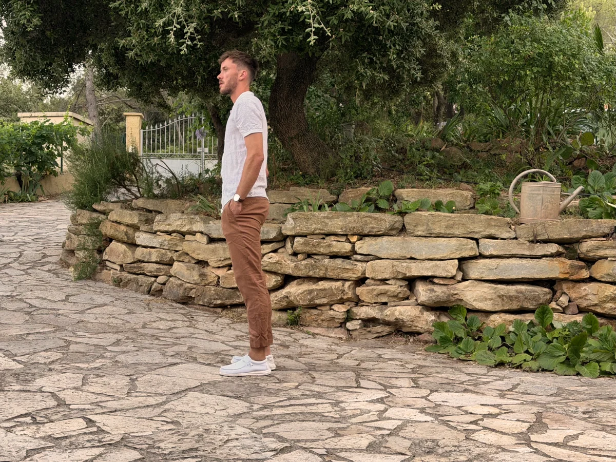 Simon Charles, architecte, fondateur d'Atomes studio, de profil devant un muret de pierres sèches